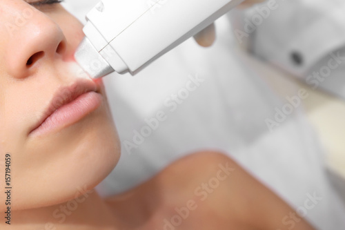Woman getting laser treatment on her face in a beauty salon, close up photo