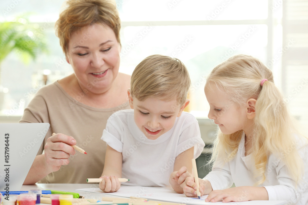 Happy senior woman painting together with grandchildren at home Happy senior woman painting together with grandchildren at home
