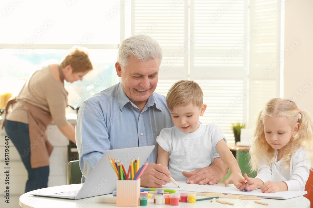 Senior man painting together with grandchildren at home Senior man painting together with grandchildren at home