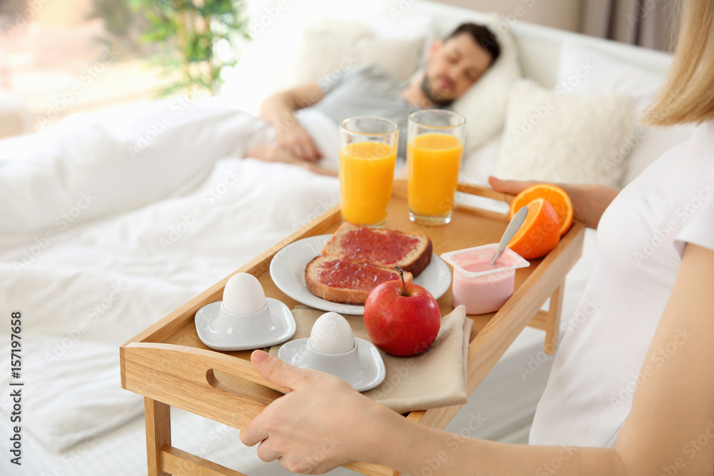 Woman bringing tray with breakfast to bed