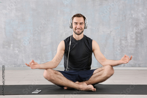 Man doing yoga and listenin...