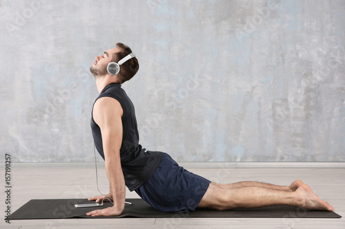 Man doing yoga and listenin...