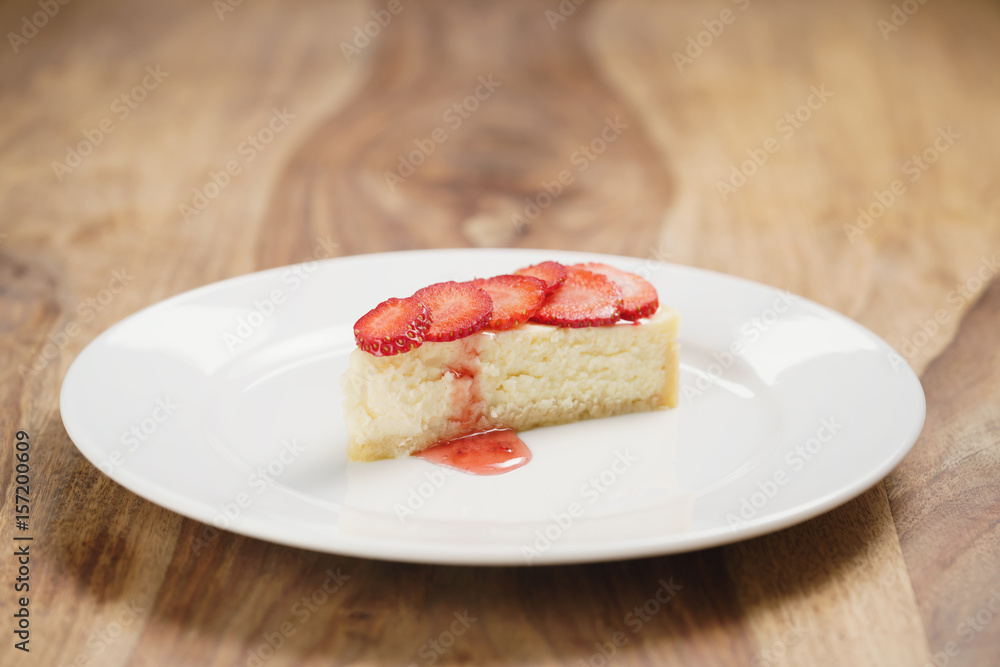 cheesecake with strawberry on plate on wood table, shallow focus