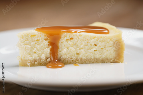 caramel sauce pour on cheesecake on plate closeup, shallow focus