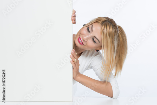 Attractive young blonde woman behing billboard or cardboard photo