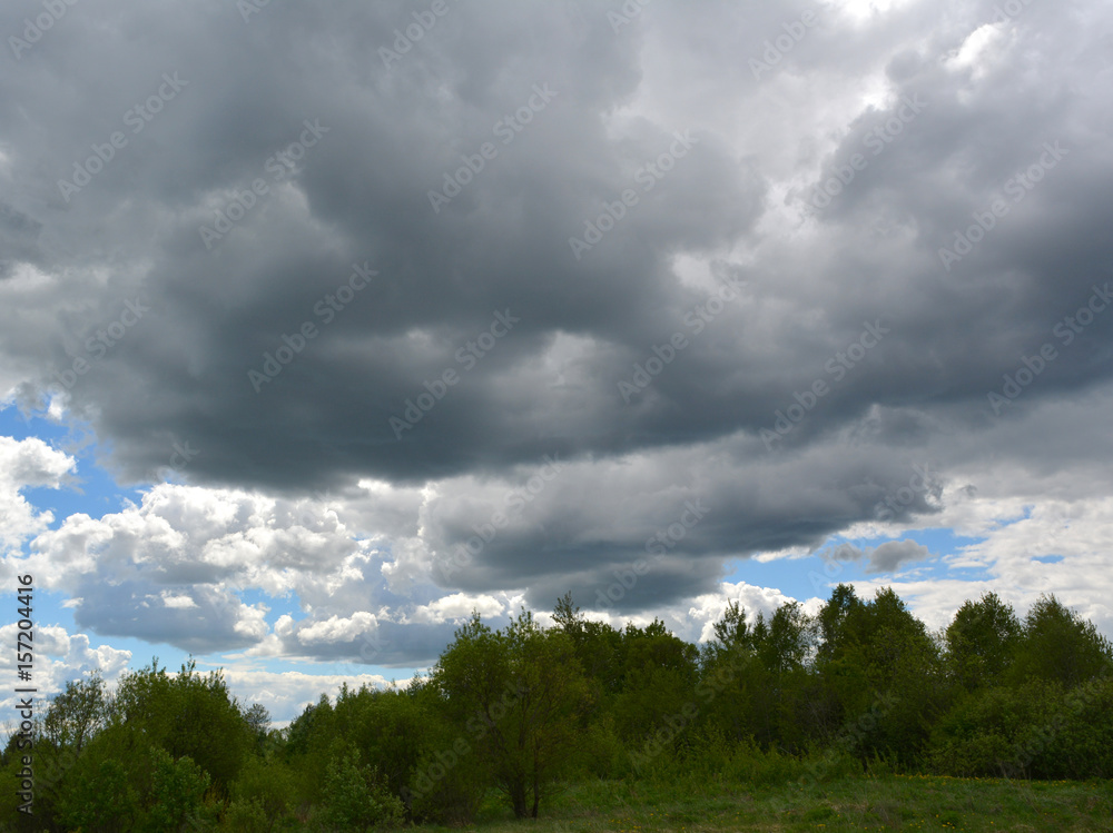 Dark clouds over a green field and trees, bad weather, nature, suburban landscape Dark clouds over a green field and trees, bad weather, nature, suburban landscape