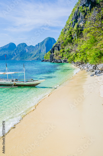 Traditional banca boat in clear water at sandy beach near El Nido, Philippines