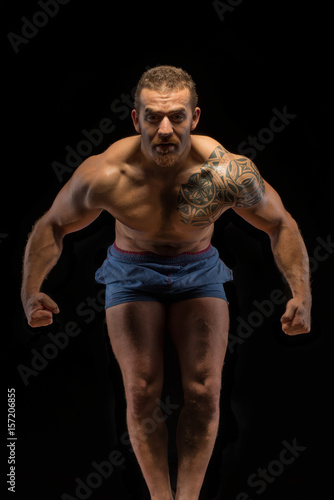 Strong and athletic man challenging the viewver with huge muscles photo