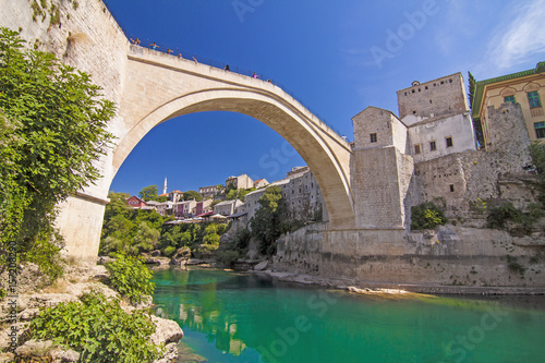 Bosnia and Herzegovina - Mostar - Old Bridge (Stari Most), UNESCO Waorld Heritage, and emerald river Neretva among rocks and old city buildings in summer sun lights