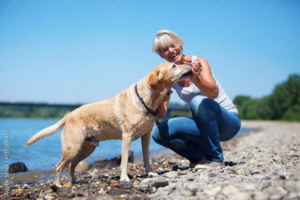 mature woman plays with a dog at the river mature woman plays with a dog at the river