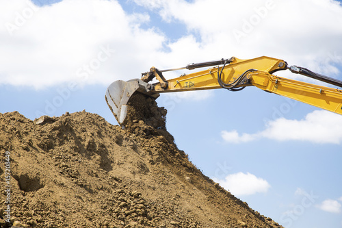 Yellow excavator loads the ground on construction site