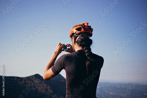 Φωτογραφία Tall male cyclist with long hair makes photo on his action camera of amazing sce
