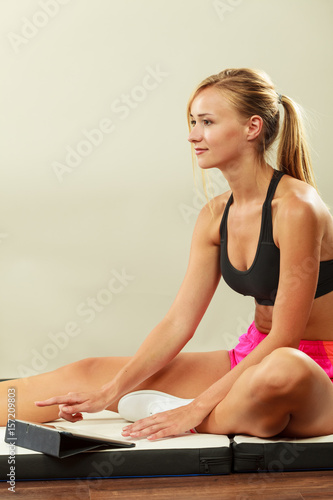 Fit woman sitting on floor with tablet pc