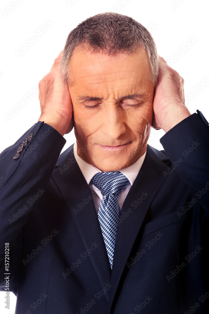 Portrait of tired man covering ears with hands