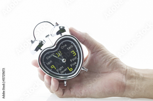 Hand holding alarm clock on white background.