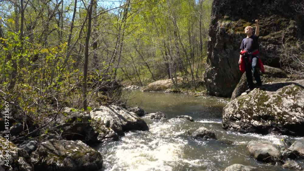 Young Man Blond Slow Motion a Forest Stream. Early Spring is a Sunny Day, a Big Stream of Water. Young Man Blond Slow Motion a Forest Stream. Early Spring is a Sunny Day, a Big Stream of Water.