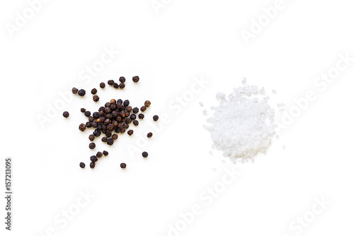Dried whole seed of black pepper and white coarse sea salt isolated on a white background seen from above