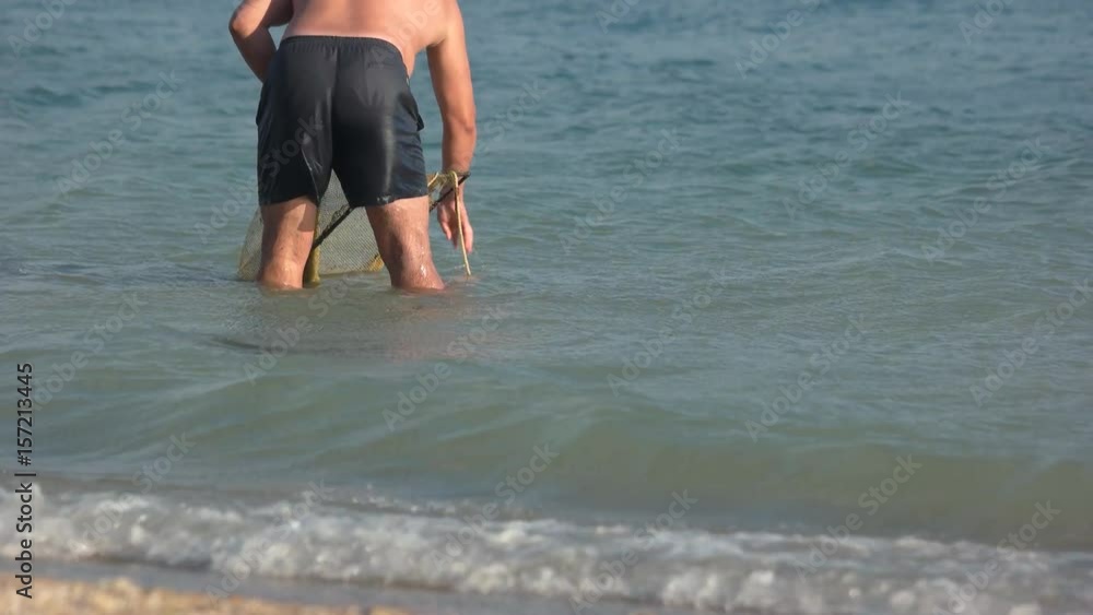 Fisherman catches a fish. Marine hobbies. Man is washing the net in the sea. Fisherman catches a fish. Marine hobbies. Man is washing the net in the sea.