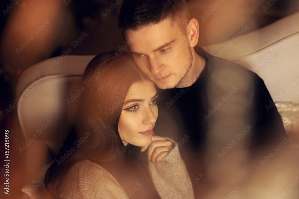 Closeup portrait of young romantic caucasioan couple sitting and higging in christmas decorated interior. Cute lovers staying at home and enjoying tome together Closeup portrait of young romantic caucasioan couple sitting and higging in christmas decorated interior. Cute lovers staying at home and enjoying tome together