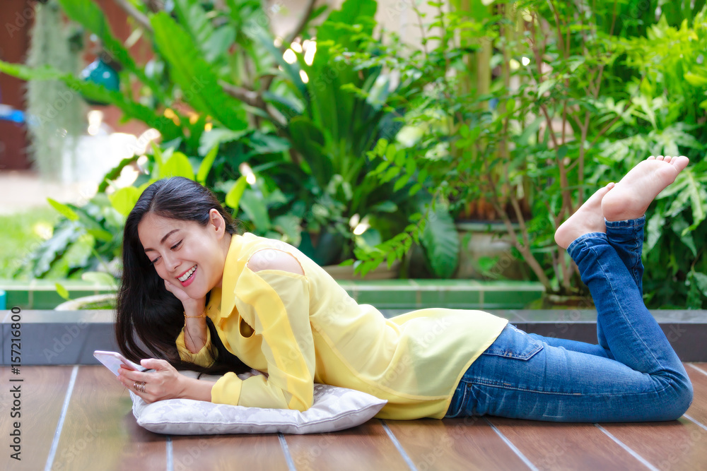 Happy asian woman smiling and using smart phone. Outdoors on summer day. Happy asian woman smiling and using smart phone. Outdoors on summer day.