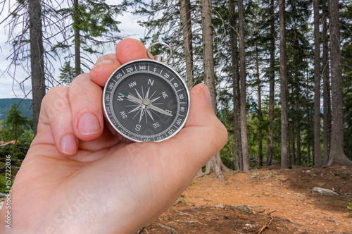 Woman with compass is seeking a right way in forest