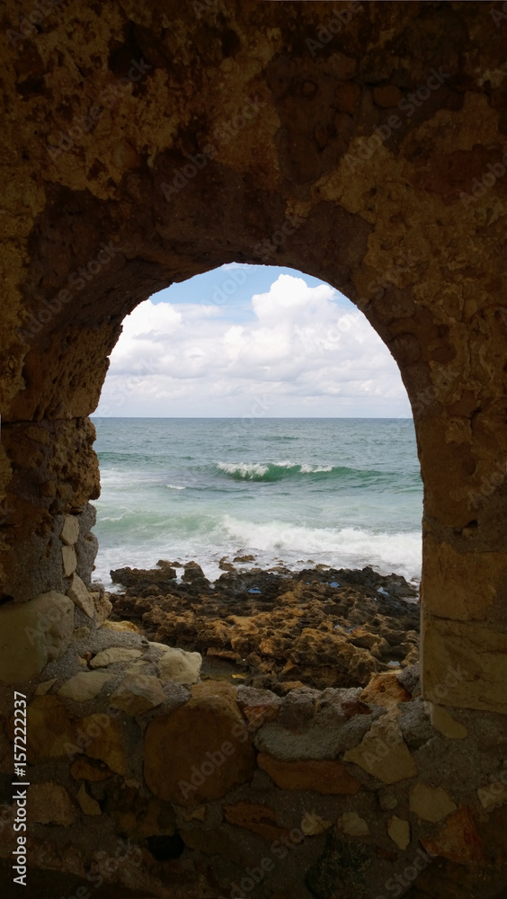 A popular site for photography in Chania - a beautiful hollow window in the destroyed old wall on the shore in Chania (Crete). Vertical view