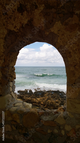 A popular site for photography in Chania - a beautiful hollow window in the destroyed old wall on the shore in Chania (Crete). Vertical view © kroshanosha