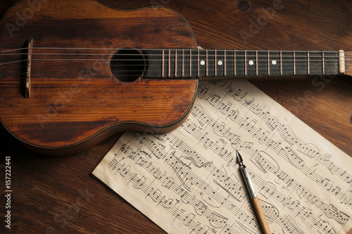 Ancient little acoustic guitar and hand-written notes on the table