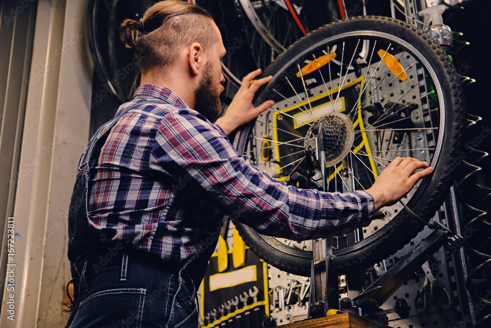 Mechanic repairing bicycle wheel tire in a workshop.
