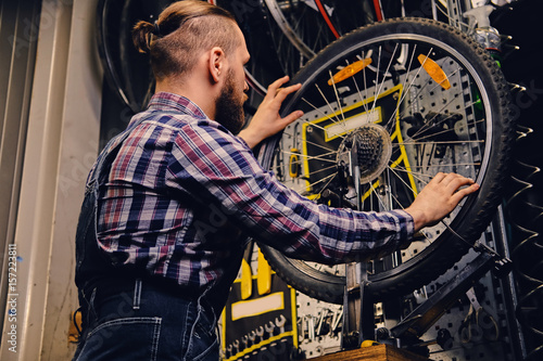Fototapeta Naklejka Na Ścianę i Meble -  Mechanic repairing bicycle wheel tire in a workshop.