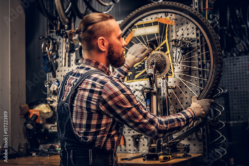 Mechanic doing bicycle wheel service manual in a workshop. © Fxquadro