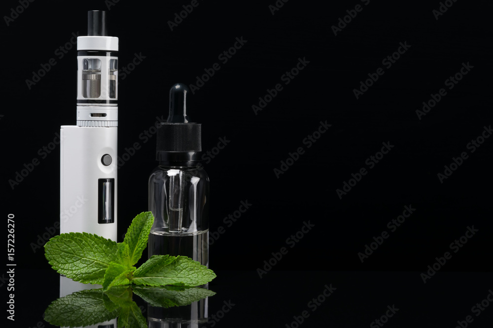 E-cigarette with reflection on a black background next to mint leaves E-cigarette with reflection on a black background next to mint leaves