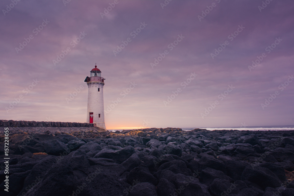 Port fairy lighthouse at sunrise with rocks