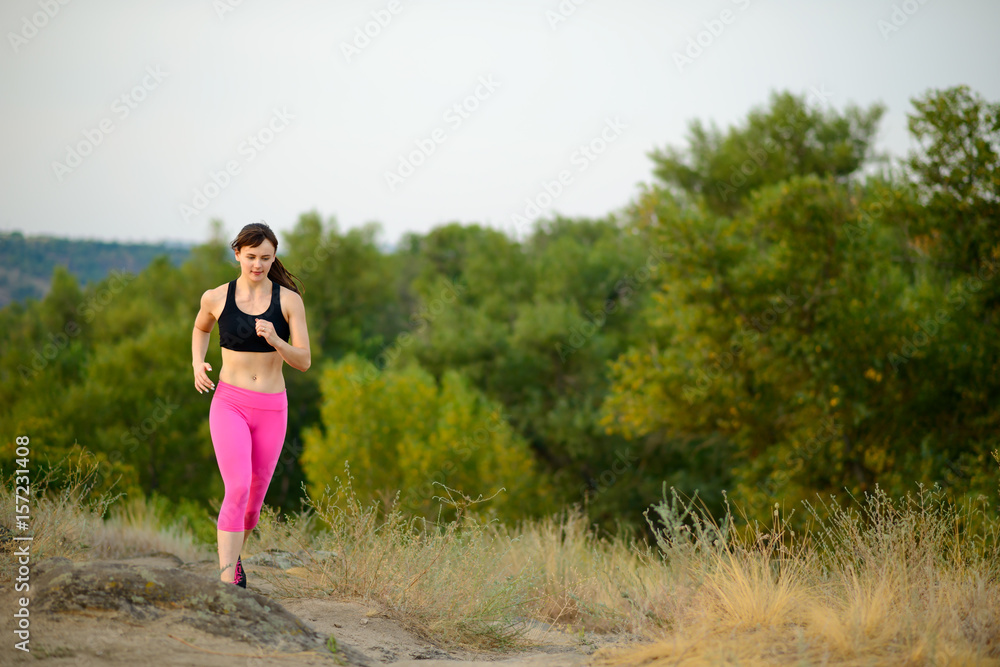Young Woman Running on the Morning Mountain Trail. Active Lifestyle Concept. Young Woman Running on the Morning Mountain Trail. Active Lifestyle Concept.
