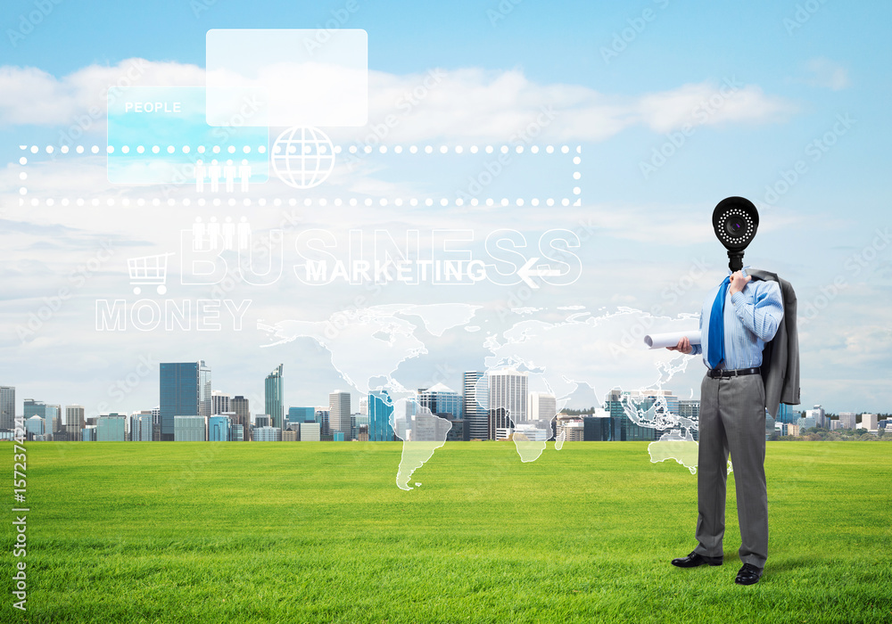 Camera headed man standing on green grass against modern cityscape Camera headed man standing on green grass against modern cityscape