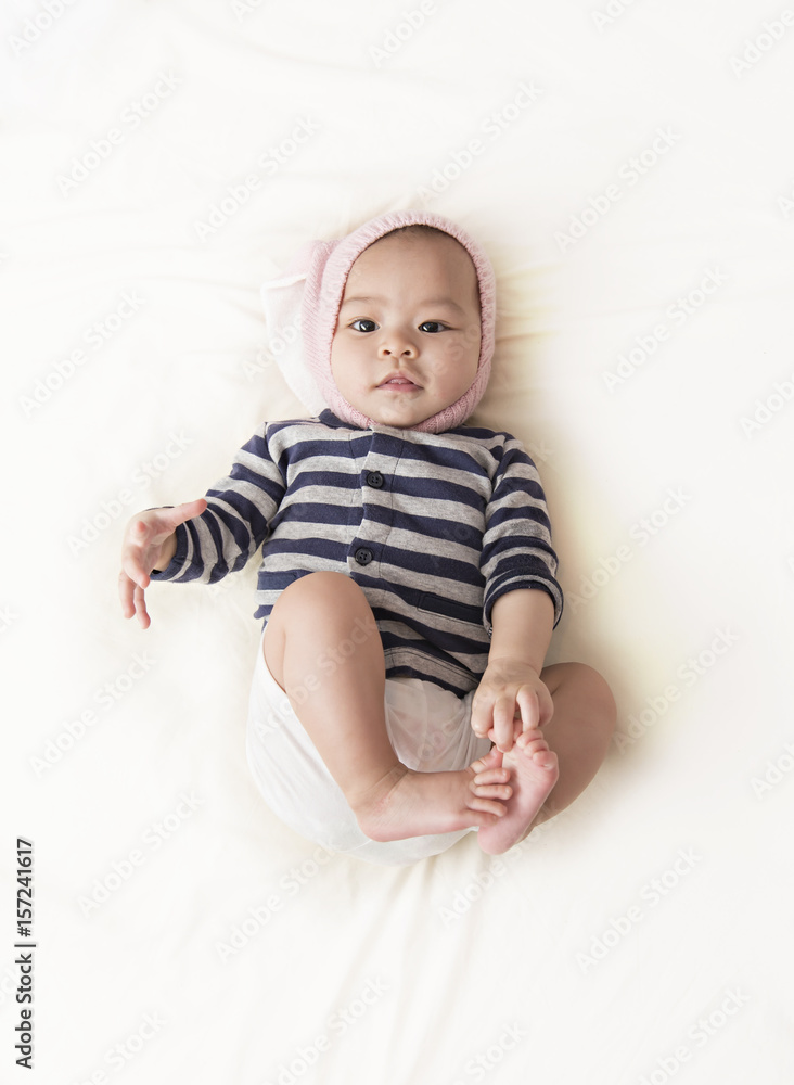 Fototapeta premium Charming Asian child. Little girl with rabbit hat lying on her stomach.