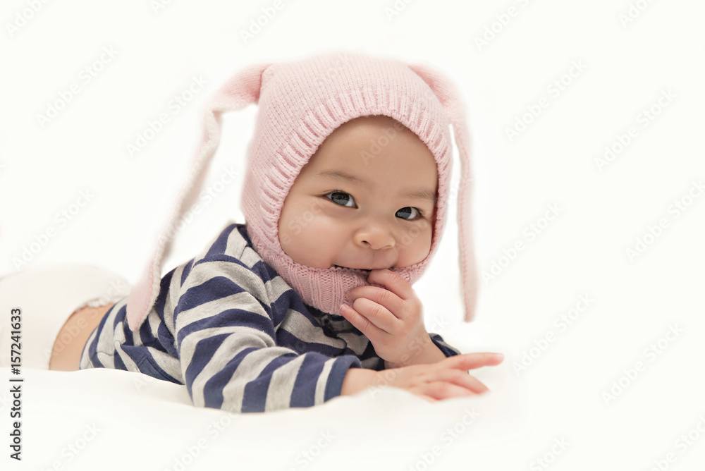 Asian cute baby girl wearing pink rabbit hat on her head on white background Asian cute baby girl wearing pink rabbit hat on her head on white background