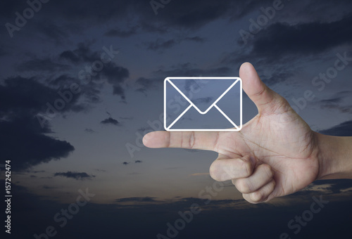 Mail icon on finger over sunset sky, Contact us concept