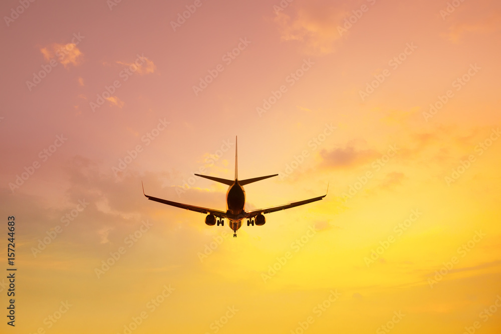 Flying airplane preparing to landing over sunset sky