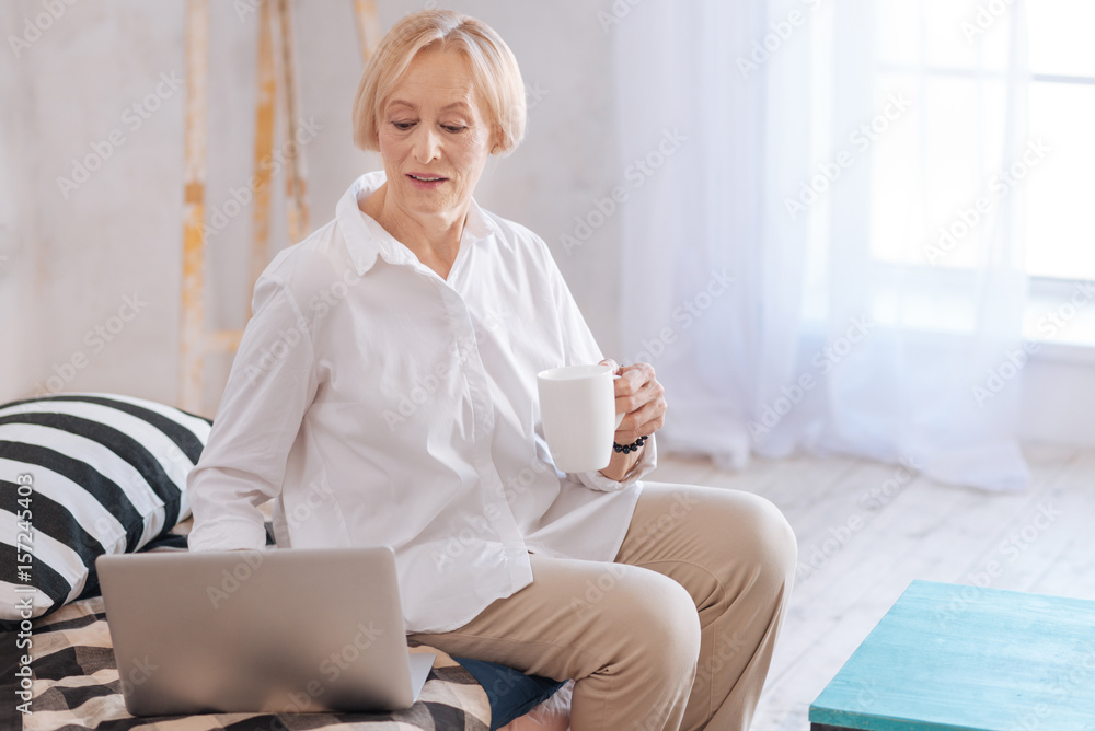 Delighted elderly woman sitting in light room of her apartments Delighted elderly woman sitting in light room of her apartments