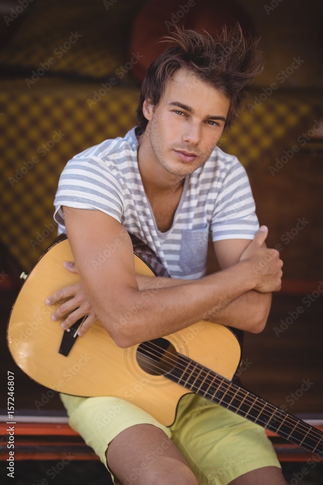 Obraz premium Portrait of handsome man with guitar sitting in van