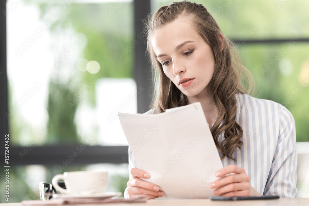 portrait of focused businesswoman doing paperwork while working in cafe portrait of focused businesswoman doing paperwork while working in cafe