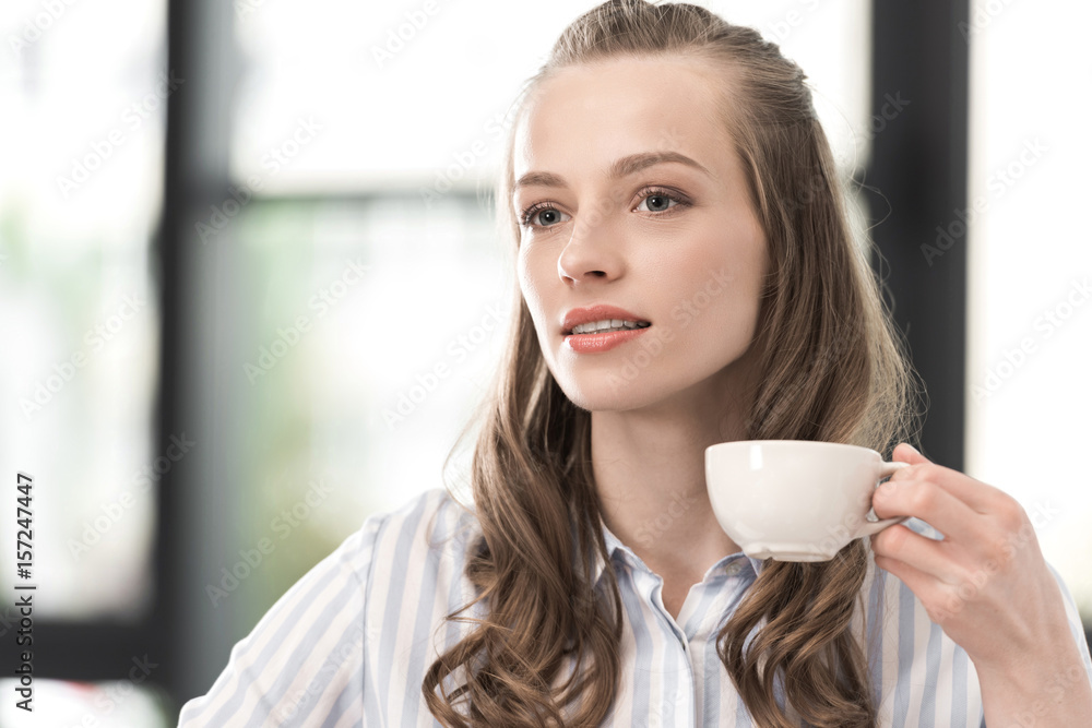 portrait of pensive woman holding cup of coffee in hand portrait of pensive woman holding cup of coffee in hand