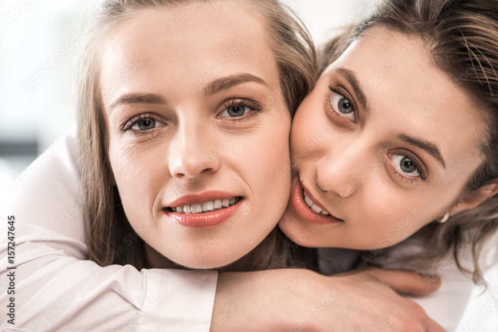 close up portrait of young smiling caucasian girlfriends embracing and looking at camera close up portrait of young smiling caucasian girlfriends embracing and looking at camera