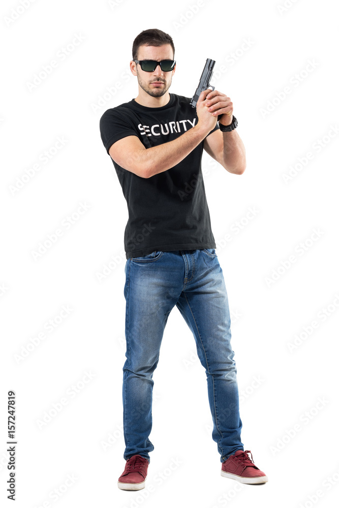 Ready alerted undercover officer holding gun in both hands looking at camera. Full body length portrait isolated on white studio background. Ready alerted undercover officer holding gun in both hands looking at camera. Full body length portrait isolated on white studio background.