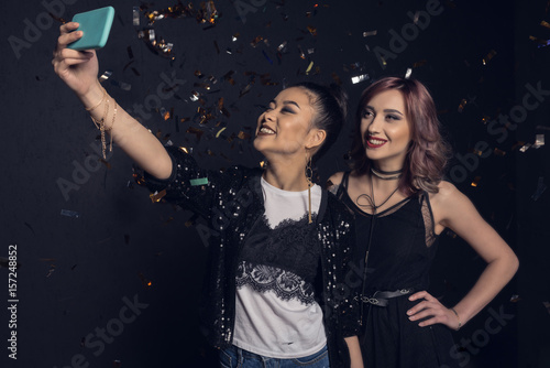 Beautiful young stylish women taking selfie with smartphone and smiling