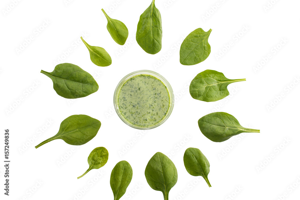 top view of green refreshing smoothie in glass standing in circle of spinach leaves isolated on white
