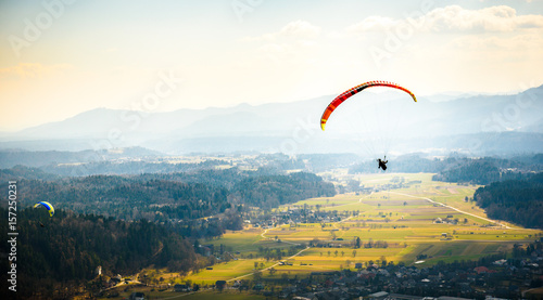 Two paragliders are flying in the valley.
