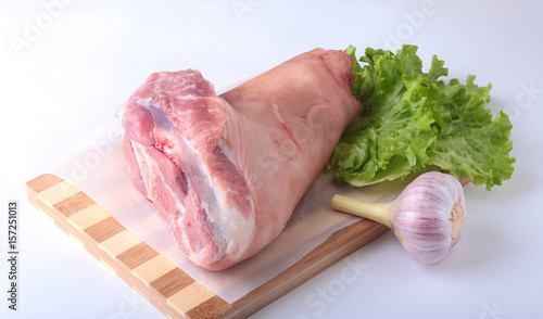 Cuadro en lienzo Raw pork knuckle, garlic and lettuce leaves on a cutting board