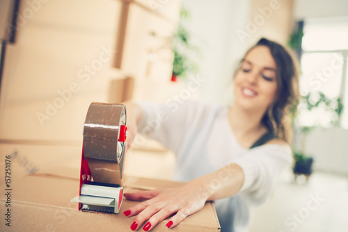 Young Caucasian girl using duct tape for packing carton boxes